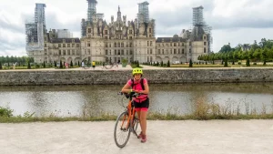 Façana monumental del Castell de Chambord amb Maria Fernandez Alonso en primer pla al costat del canal del riu Cosson. Viatge de Cicloturisme, le Loire à Vélo.